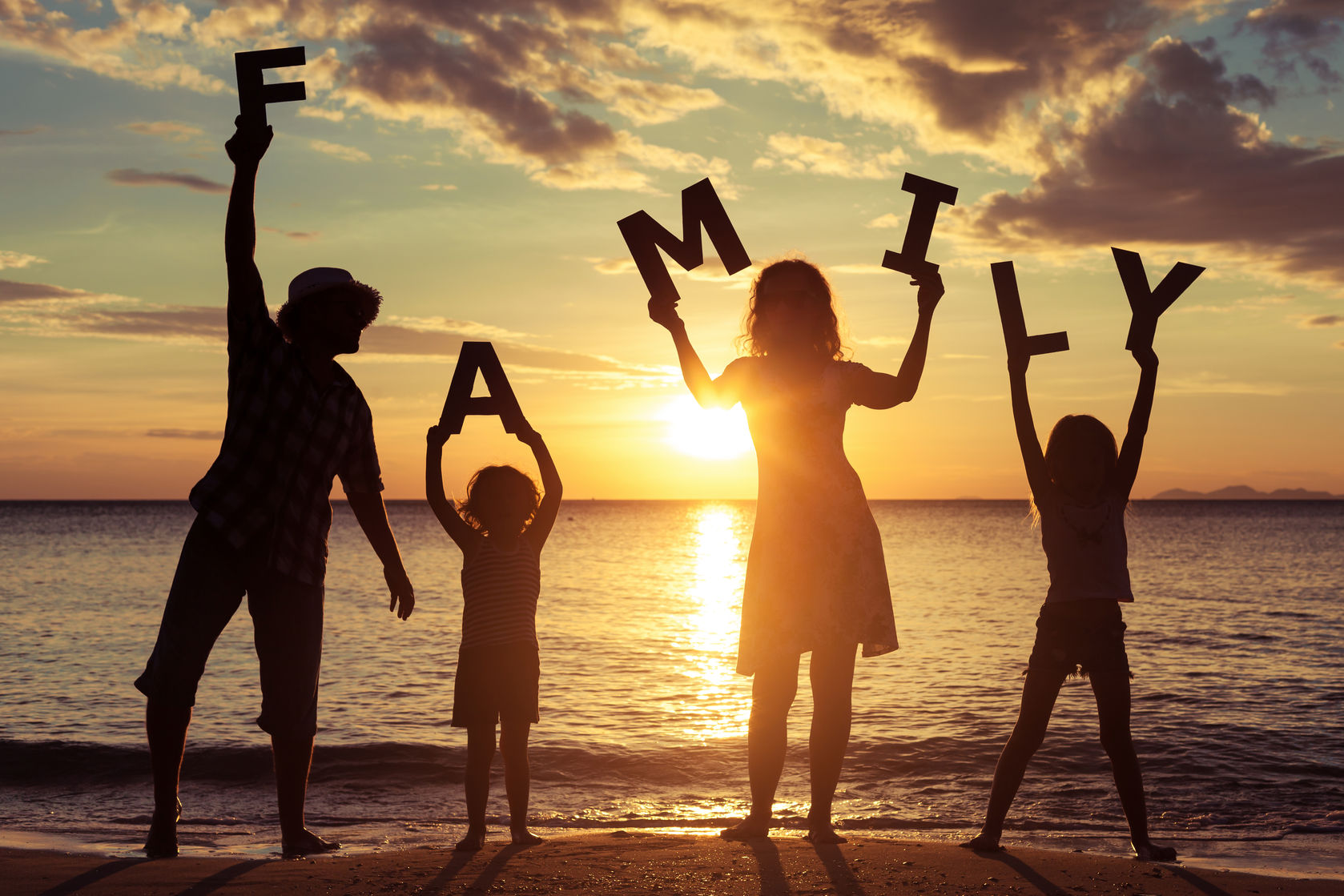 44757397 - happy family standing on the beach at the sunset time. they keep the letters forming the word " family". concept of friendly family.