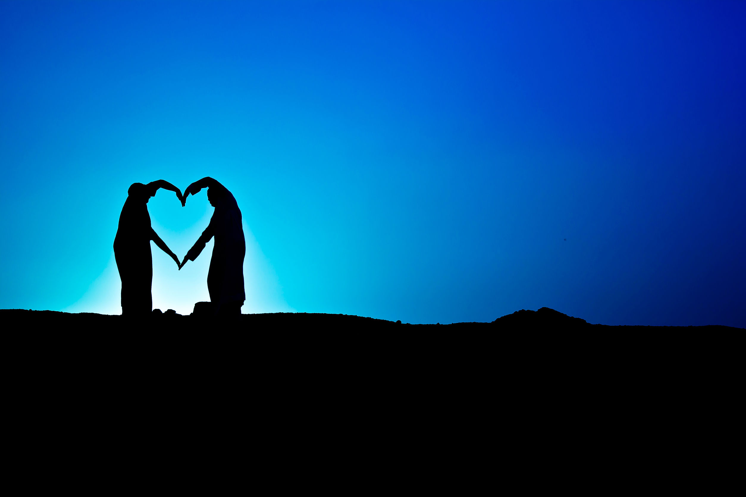 61861741 - conceptual heart shape, symbol of human. woman and man hand silhouette over sky at sunset background, metaphor to love, valentine day, romantic, couple, wedding, romance, summer or sunrise